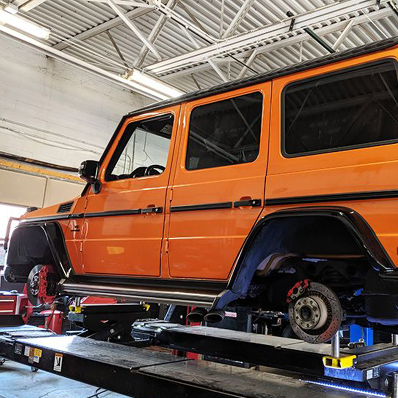 Orange Car without Tires Being Maintenanced